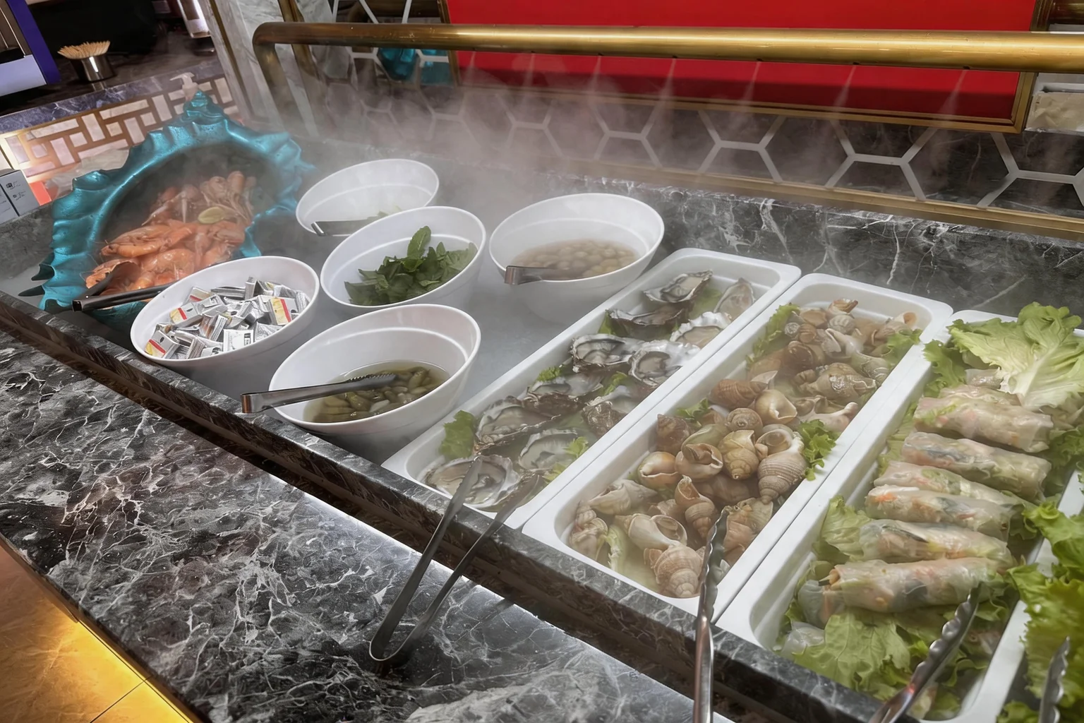Bar à fruits de mer du buffet avec huîtres, bulots et crevettes sur glace, vapeur au-dessus des bacs