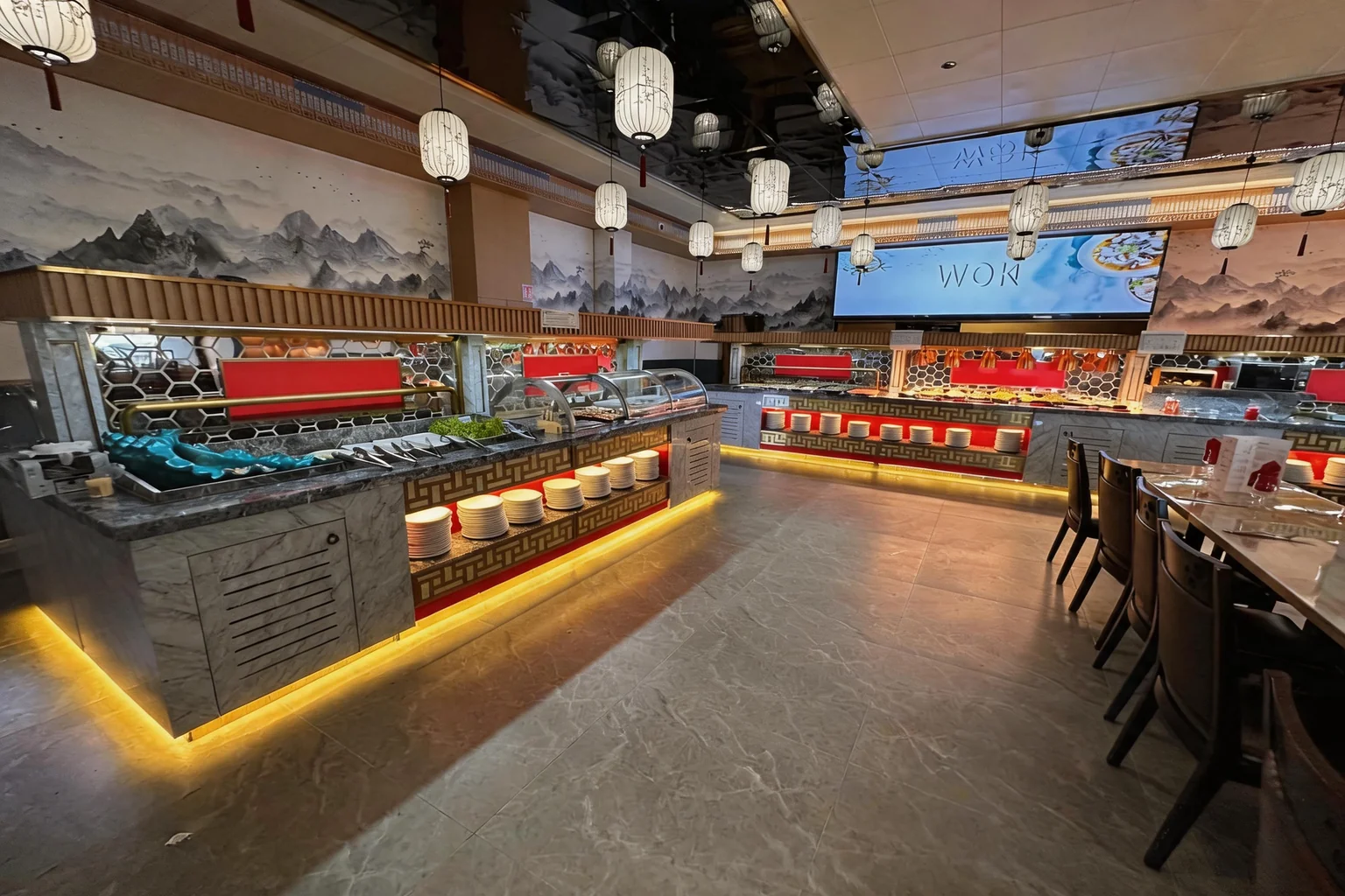 Comptoirs du buffet avec écran lumineux affichant WOK, sous une fresque de montagnes à l'encre